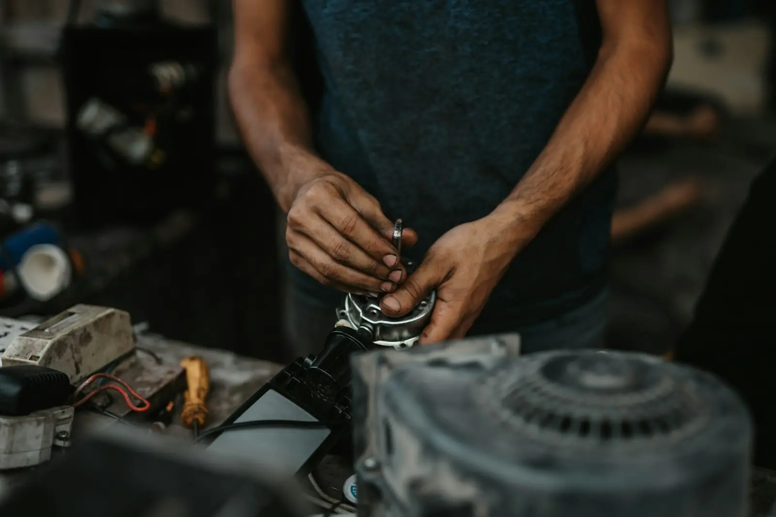 Mãos reparando um motor mecânico ao ar livre, close-up
