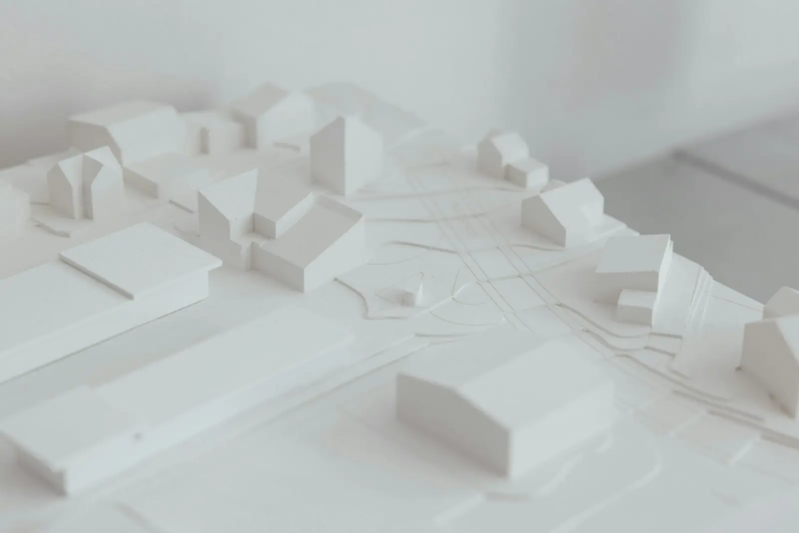 Maquete arquitetônica branca sobre mesa de estudo, vista de cima, sem pessoas
