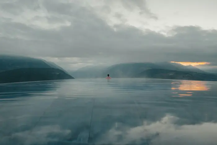 Piscina de borda infinita diante de um lago entre montanhas