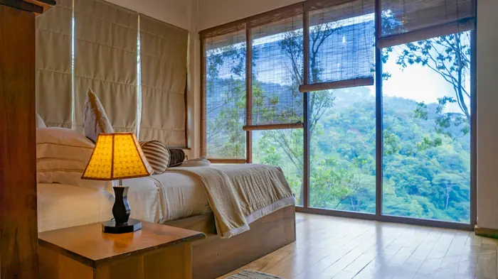 Quarto com janelas amplas abertas para a mata