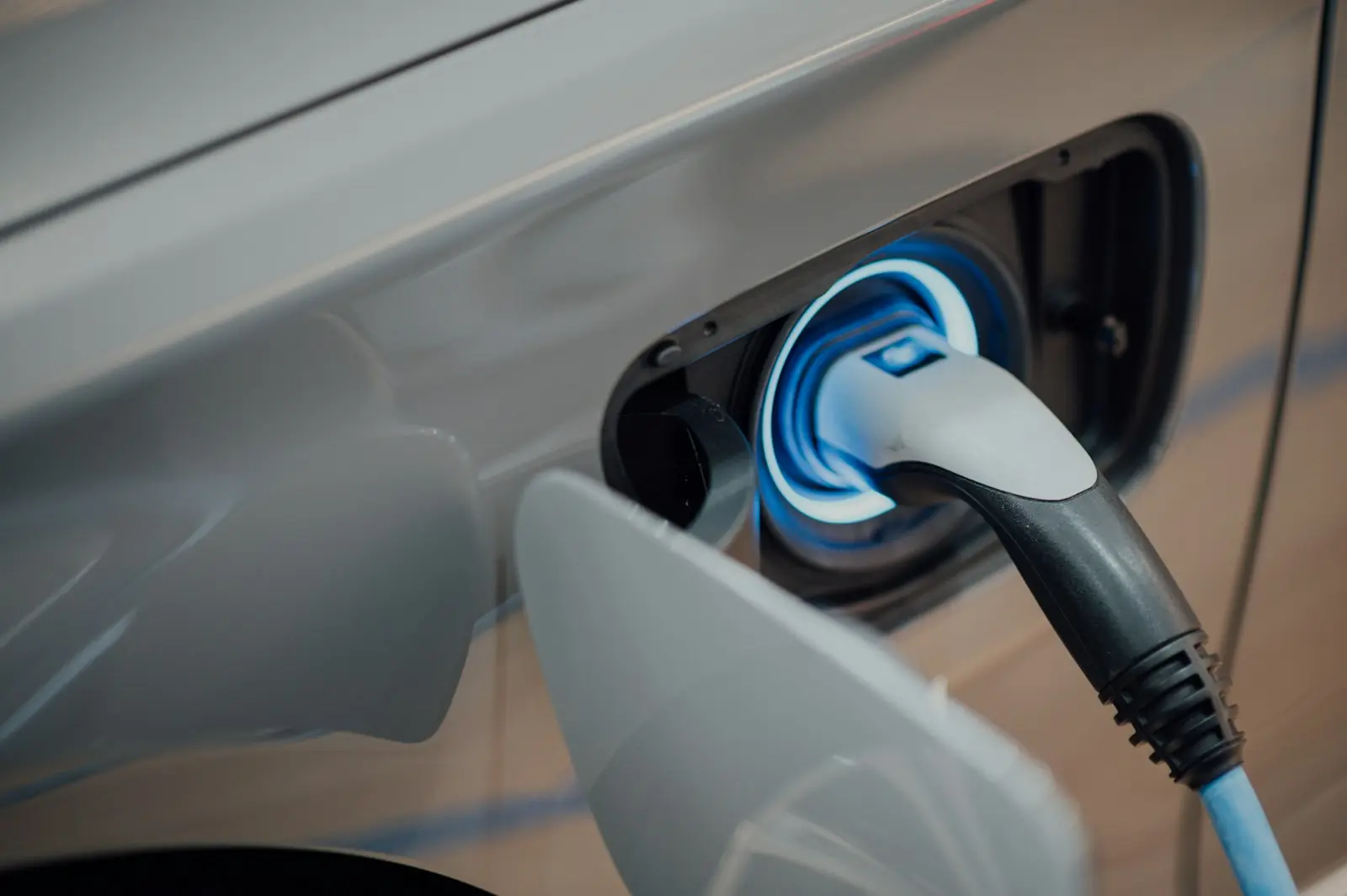 Detalhe do plugue de carregamento conectado ao carro, anel de luz azul suave, sem marca visível