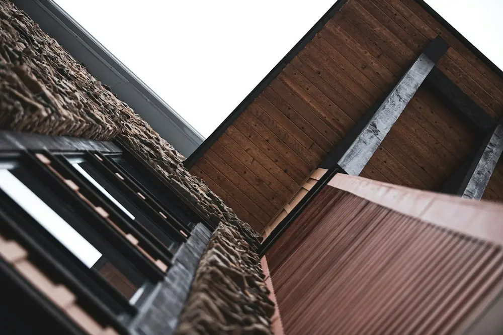 Fachada contemporânea vista de baixo, beirais em madeira contra o céu claro